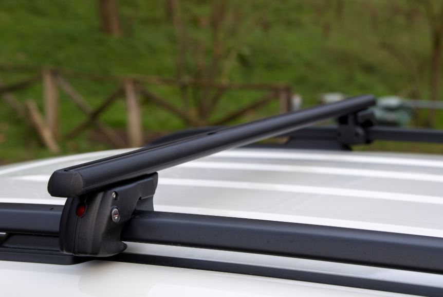 une barre de toit noire fine fixée sur des barres d'origine d'un véhicule