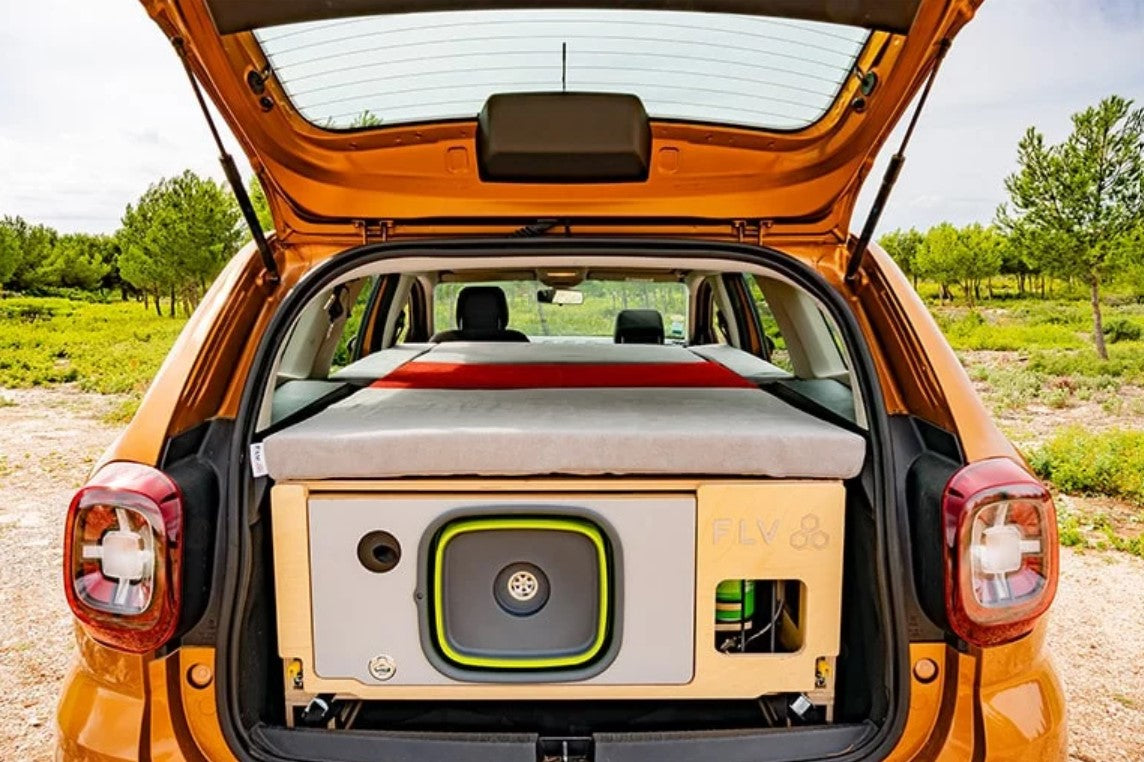 Dacia Duster orange coffre ouvert avec un aménagement en bois et un matelas