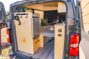 intérieur d'un van aménagé avec un espace cuisine et lit