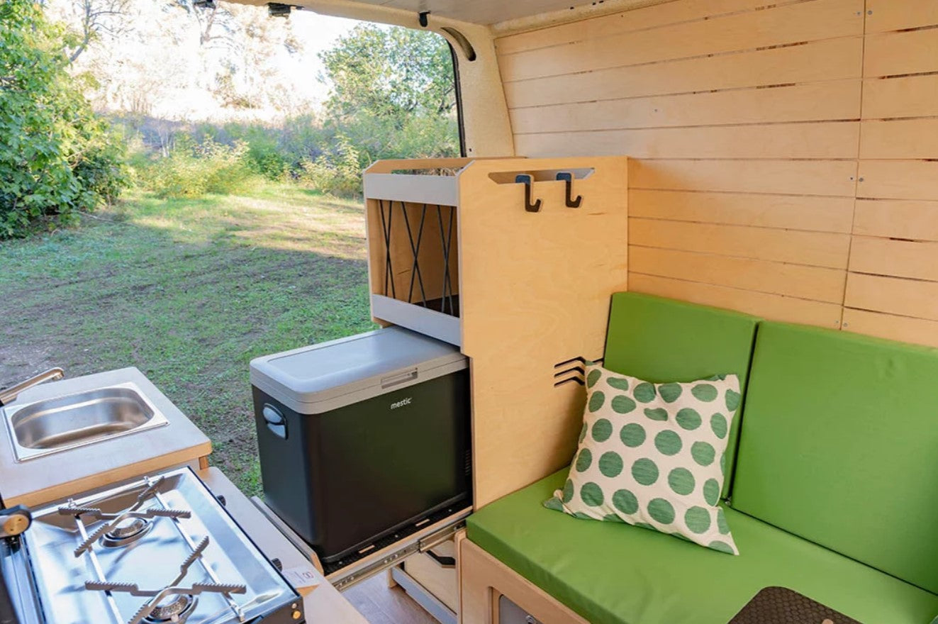 banquette verte dans un fourgon avec des meubles et un frigo