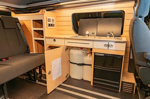 module d'un van aménagé avec deux bidons d'eau sous l'espace cuisine