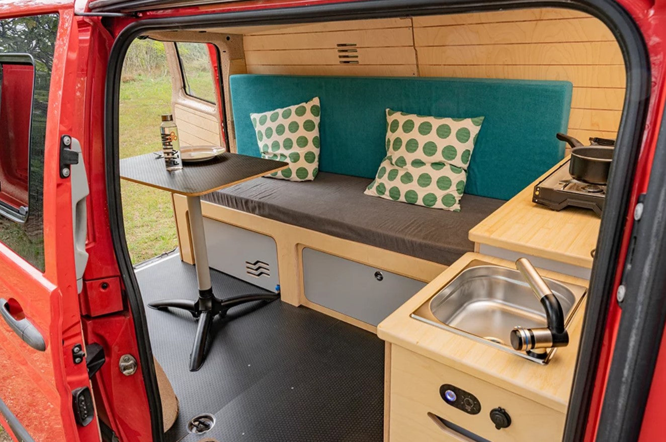 Aménagement de van avec un lit et une table dans un fourgon rouge