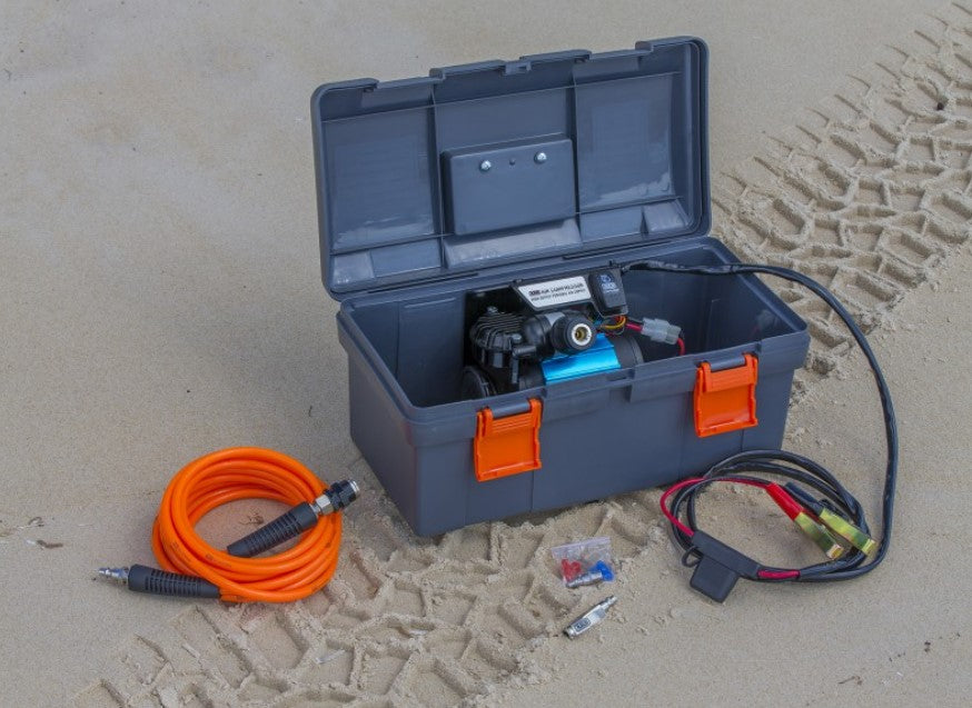 mallette grise avec un compresseur dedans posée sur le sable