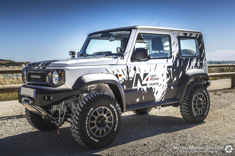 suzuki jimny blanc et noir présenté sur un chemin