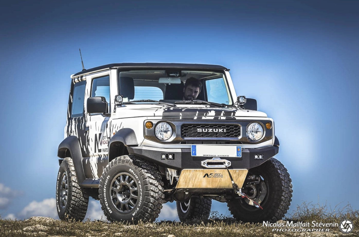 vue de face d'un suzuki jimny avec une protection en alu et un ciel bleu