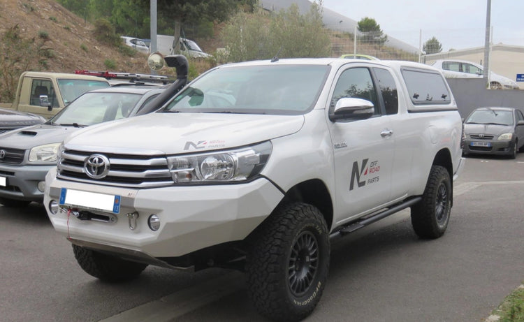 Toyota Hilux blanc garé avec un snorkel et un pc acier