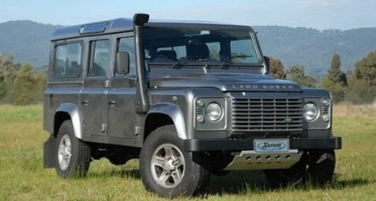 land rover defender 110 vert dans l'herbe avec un snorkel noir